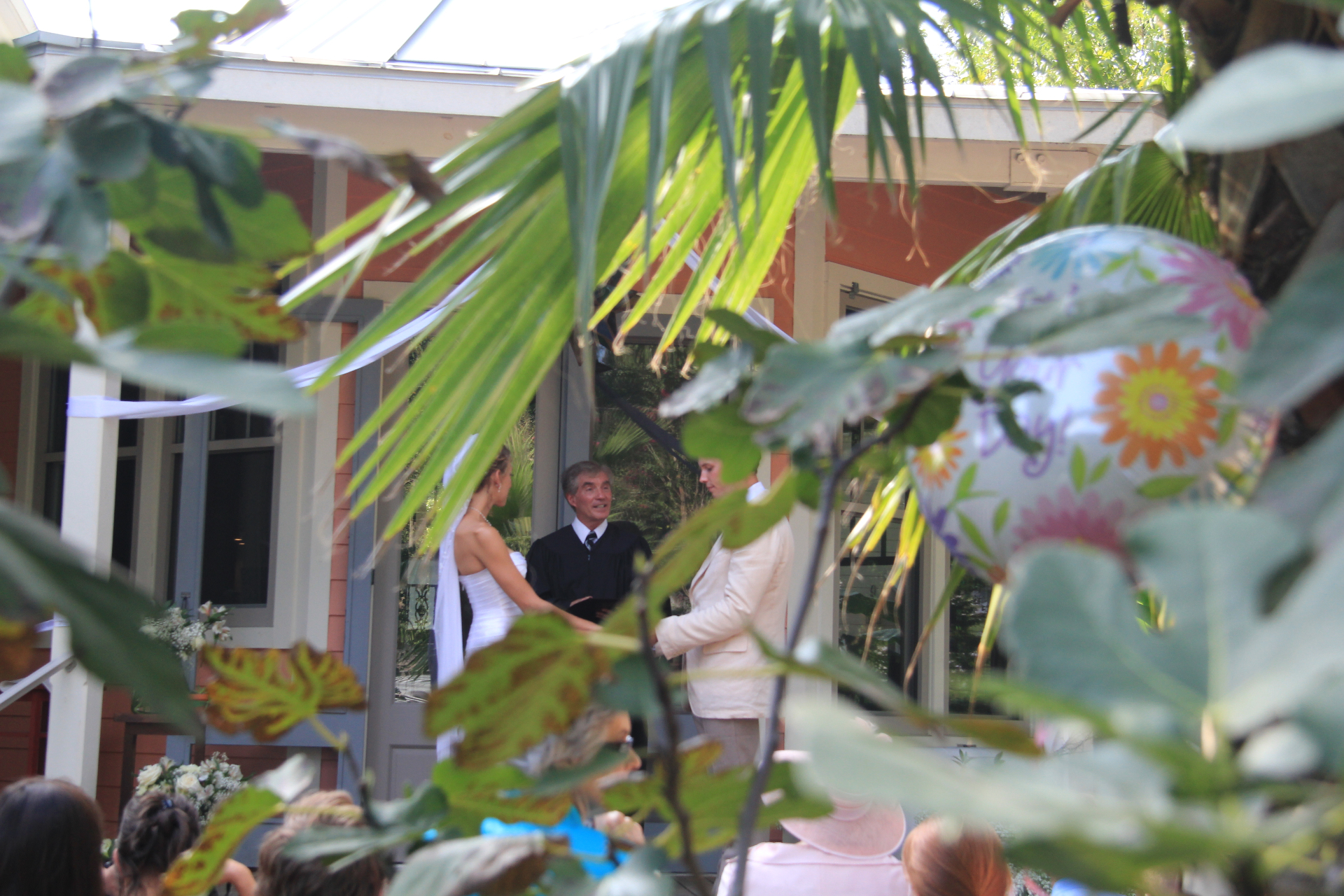 Judge Wisser officiating a garden ceremony framed by tropical palms